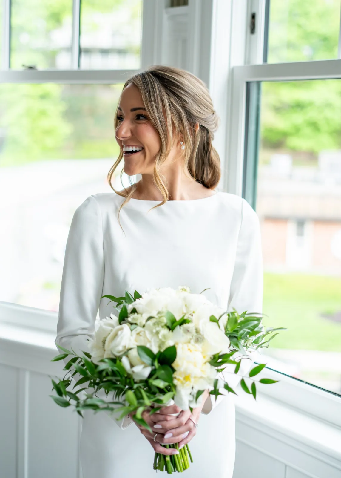 Bride laughing in window light with a white peony bouquet, Long Island bridal portrait
