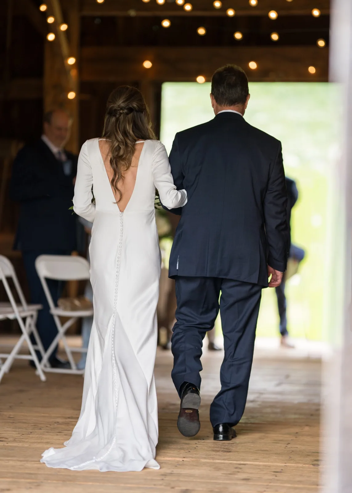 Father walks the bride down the aisle of a string-lit barn, Long Island wedding photography